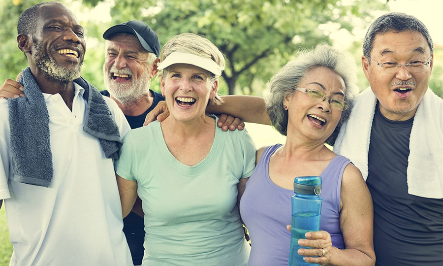 A group of physically active people of varied ages, genders, races, ethnicities laugh together