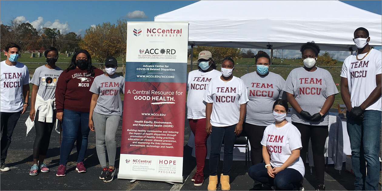 A group of ACCORD team members posing for a photo in front of a white tent.