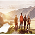Four friends stands on view point and looking at sunset mountains and river. 
