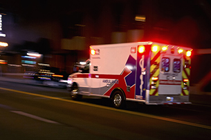 An ambulance speeding through traffic at nighttime.