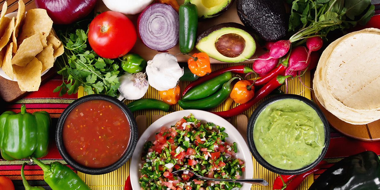 Photo: A table full of fresh tomatoes, onions, garlic, avocado, a variety of peppers, cilantro, radishes, guacamole, salsa and tortillas