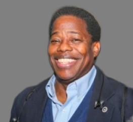 Black man smiling with blue collar shirt and jacket